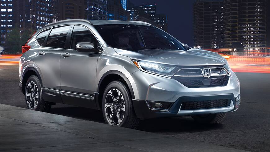 Front 3/4 view of 2019 Honda CR-V Touring in Lunar Silver Metallic showing full LED headlights with auto-on/off.