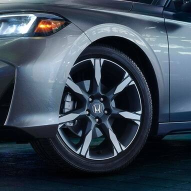 2027 Honda Civic Hatchback Sport Touring Hybrid in Solar Silver Metallic profile in a modern studio setting (Compact Hatchback).